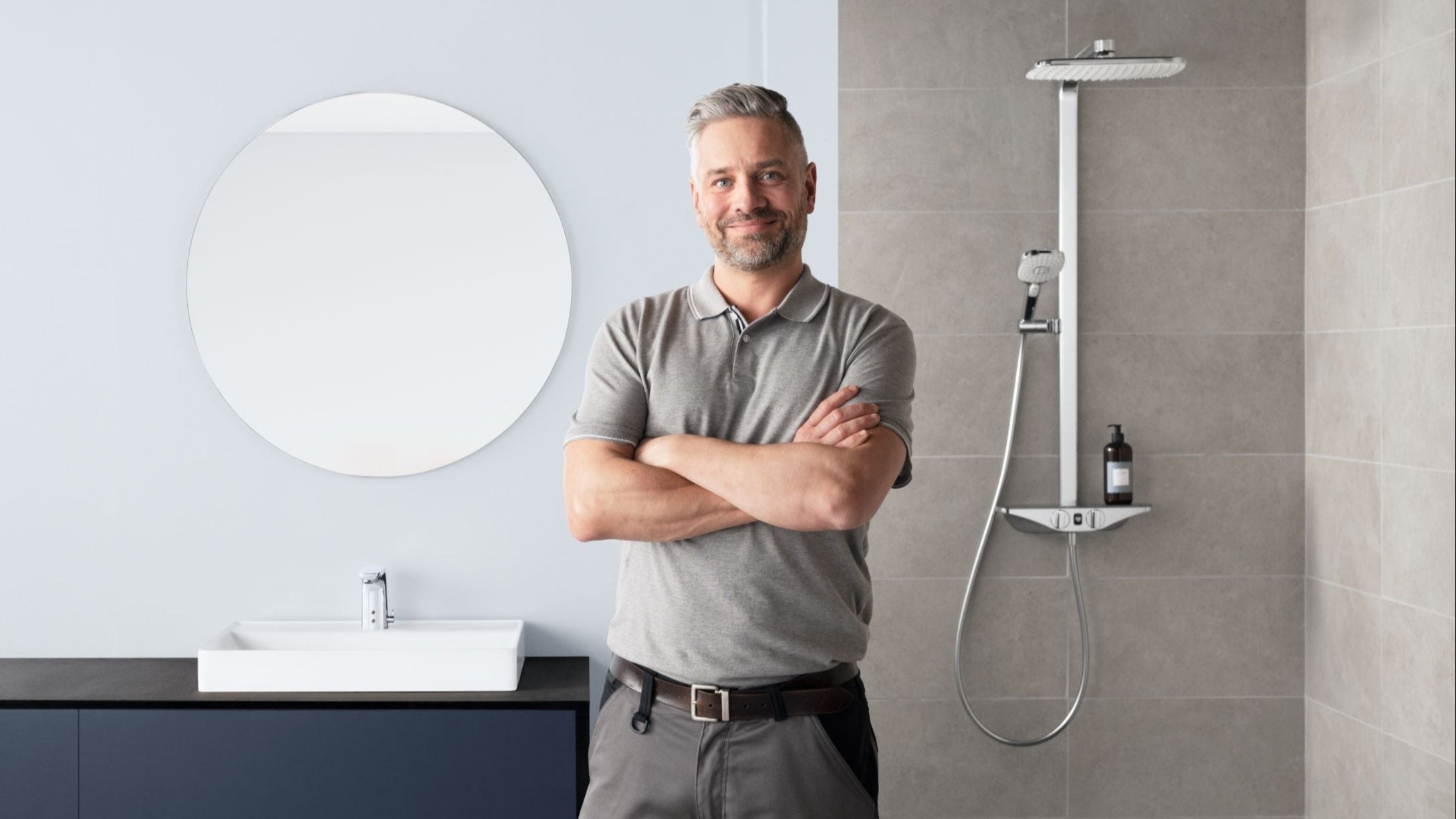 Man standing in a modern bathroom with a shower setup.